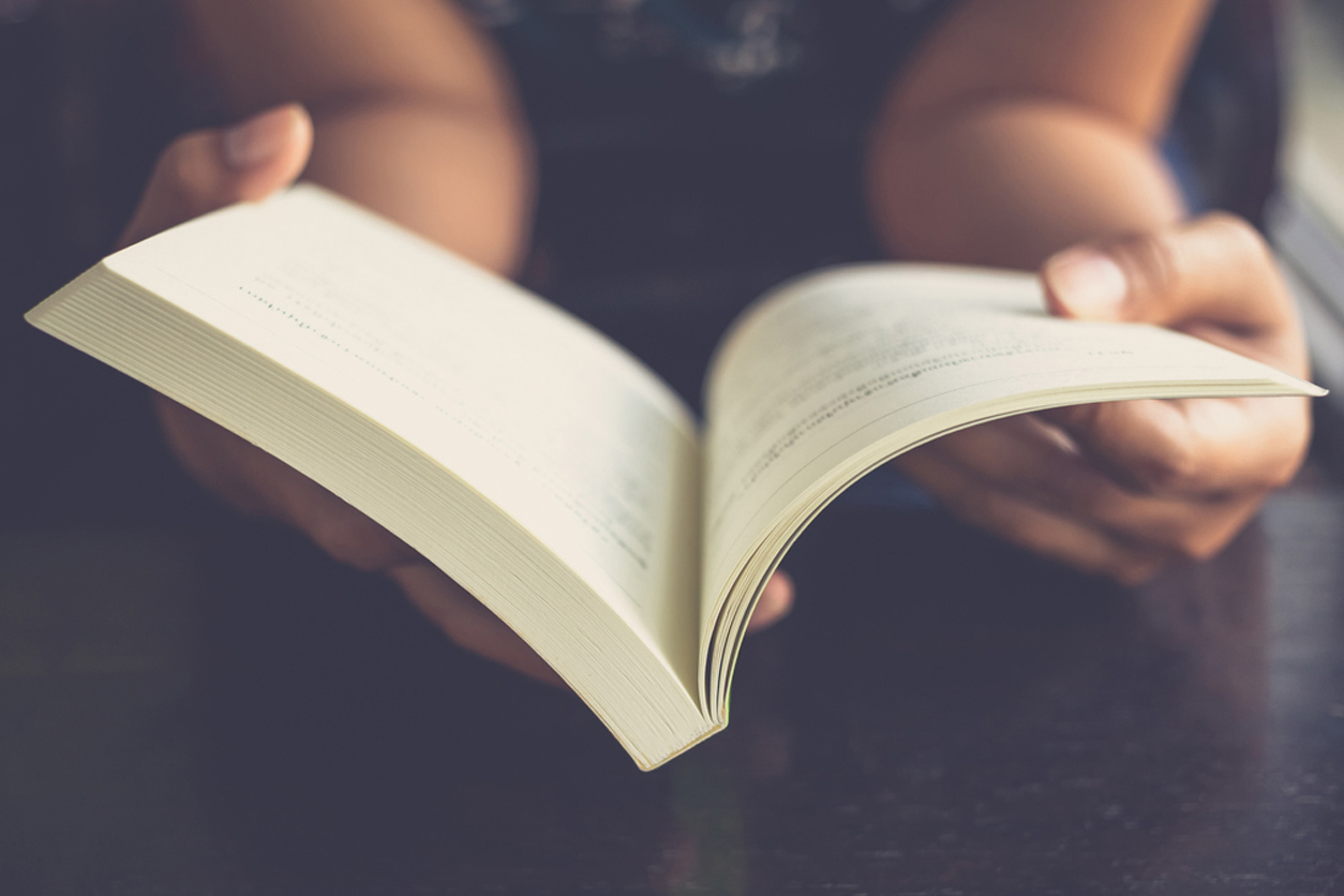 Person holding an open book symbolizing the company's history and story