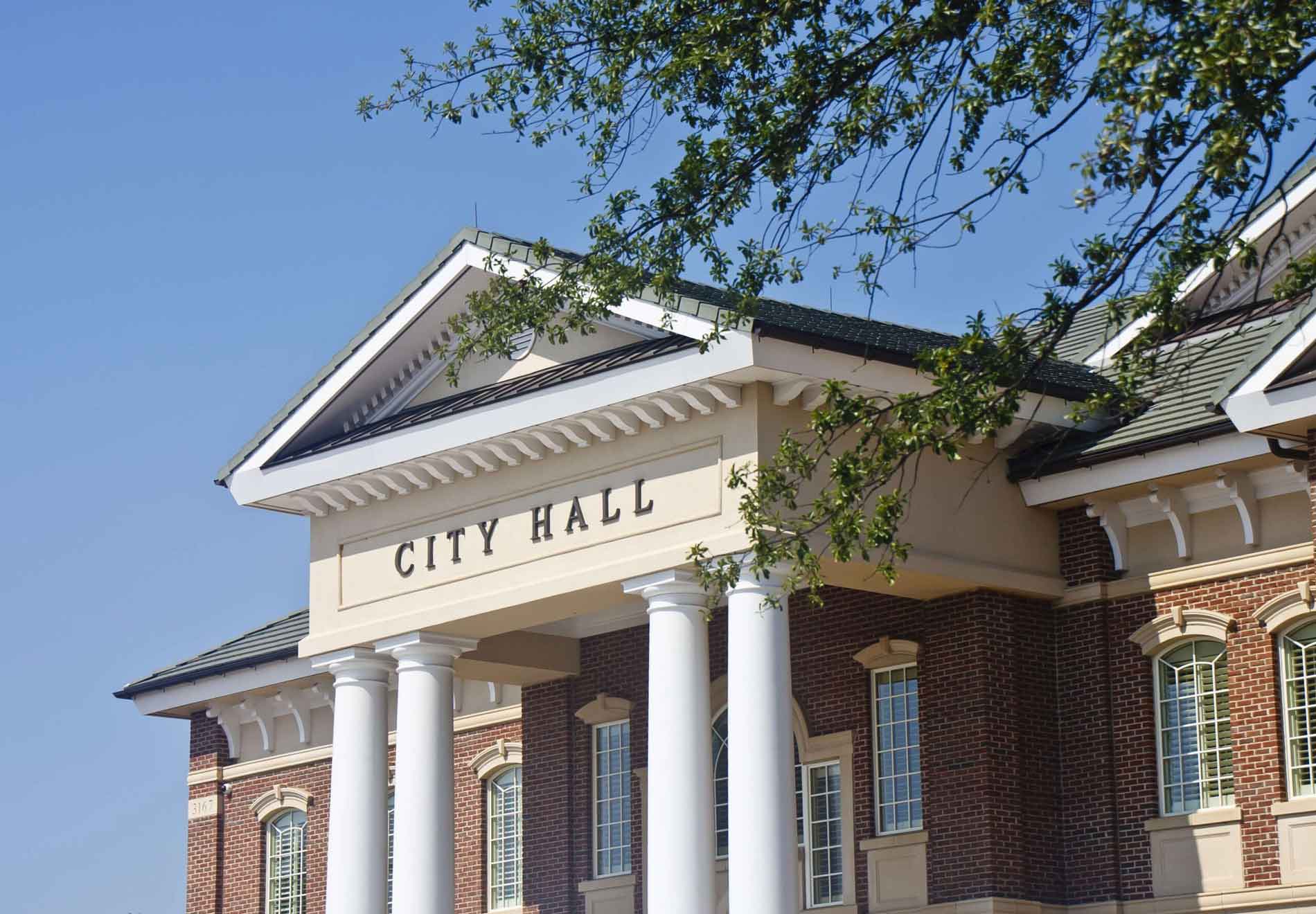 city hall building with classical columns and brick facade against blue sky symbolizing government technology